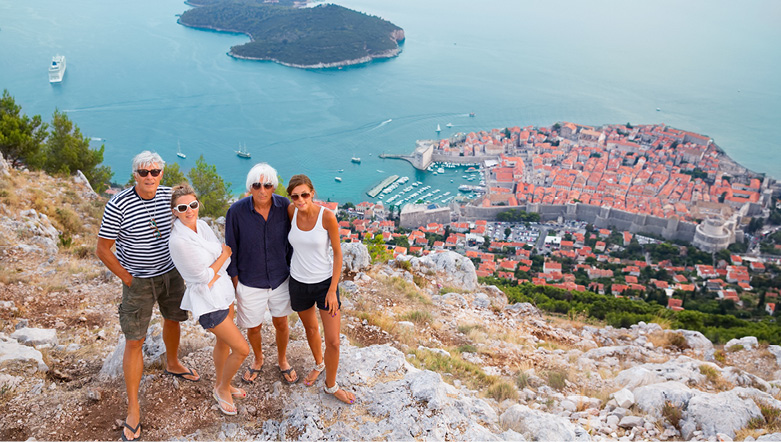 Group of friends posing for a photo on a clifftop in overlooking Dubrovnik in Croatia along the beautiful Adriatic Coast